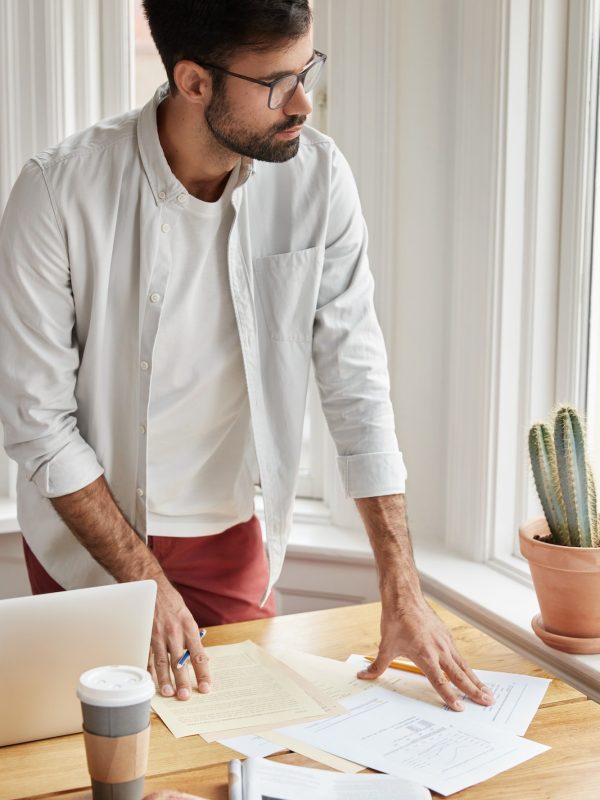 vertical-shot-of-male-coworker-cant-make-right-accountings-in-papers-looks-at-documents-planner-st.jpg